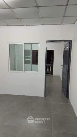 Minimalist interior with tiled floor and sliding window, ideal for office or study space.