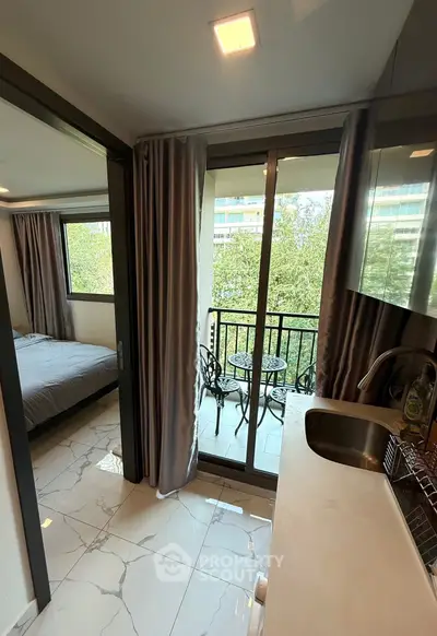 Modern apartment with balcony and sleek kitchen design, featuring large windows and elegant flooring.