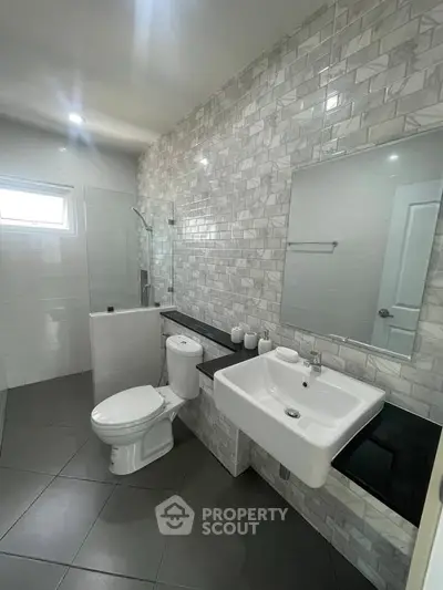 Modern bathroom with sleek design, featuring a glass shower and stylish tile work.