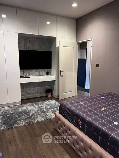 Modern bedroom with built-in wardrobe and sleek TV setup, perfect for stylish living.