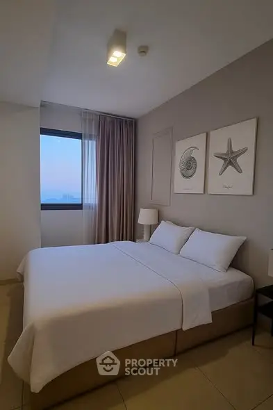 Cozy bedroom with modern decor and large window offering natural light.