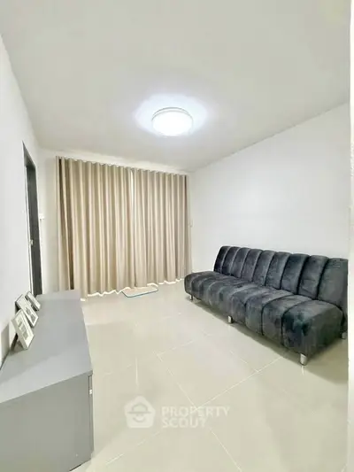Spacious living room with modern sofa and elegant curtains, perfect for relaxation and entertainment.