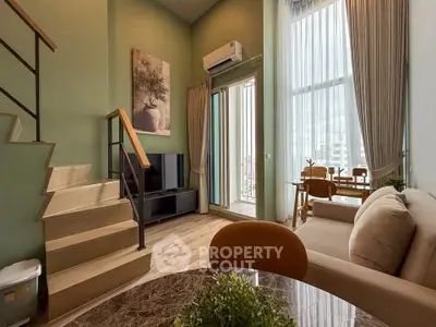 Modern duplex living room with high ceilings, stylish decor, and large windows offering city views.