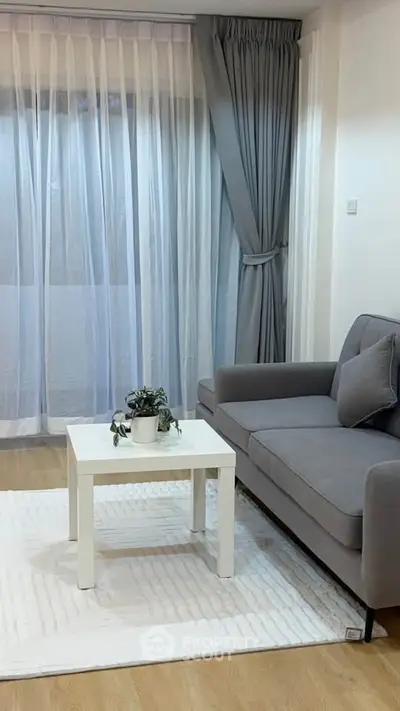 Modern living room with gray sofa, white coffee table, and elegant curtains.