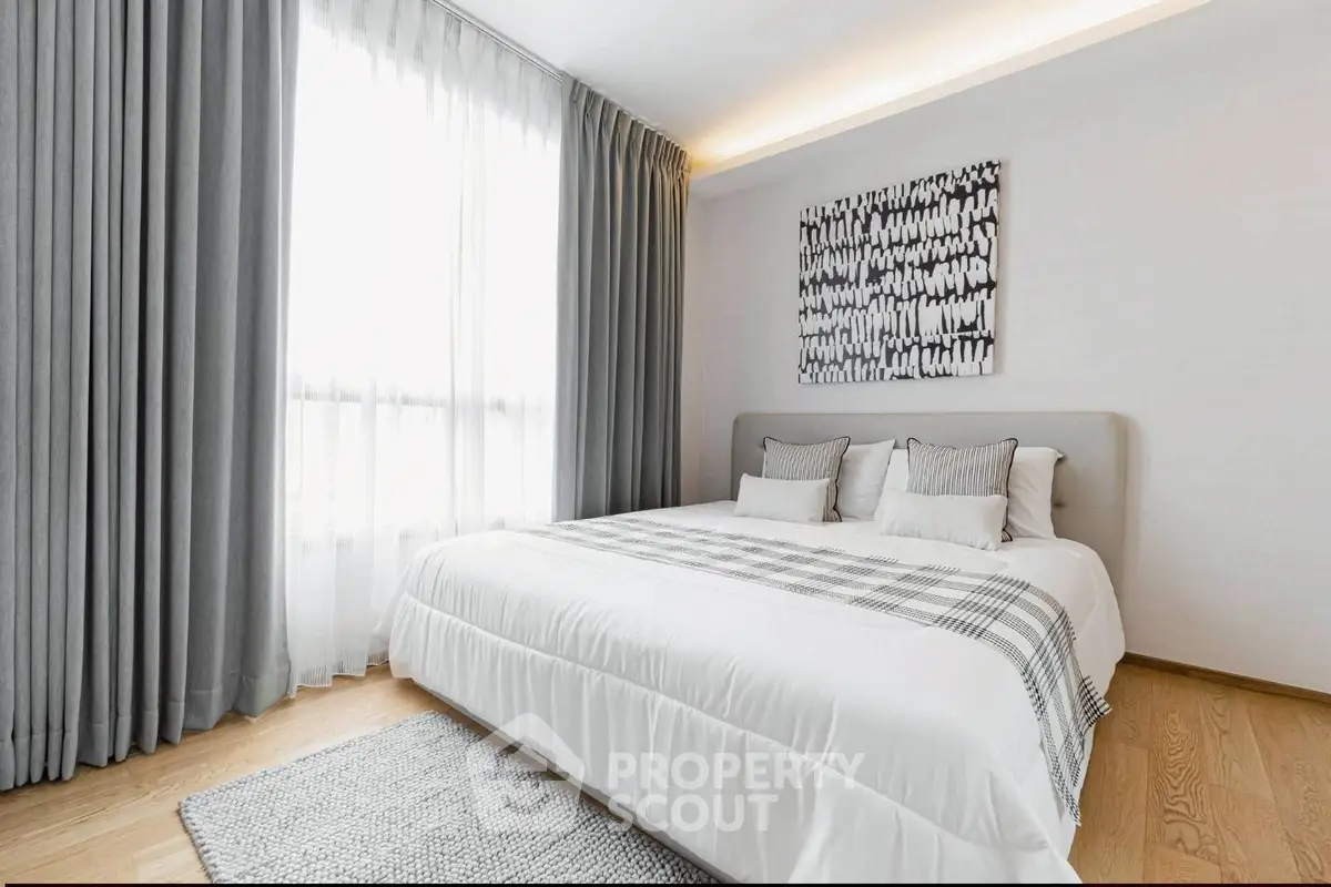 Elegant bedroom with modern decor and large window, featuring stylish curtains and cozy bedding.
