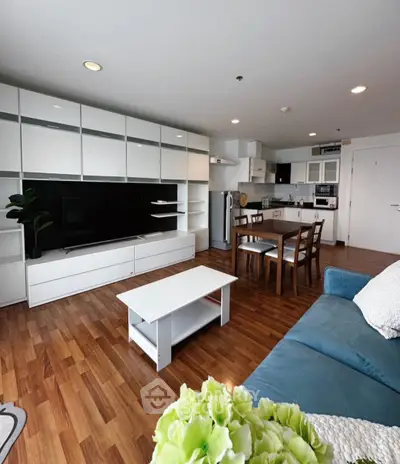 Modern open-plan living room with sleek kitchen, hardwood floors, and stylish furniture.