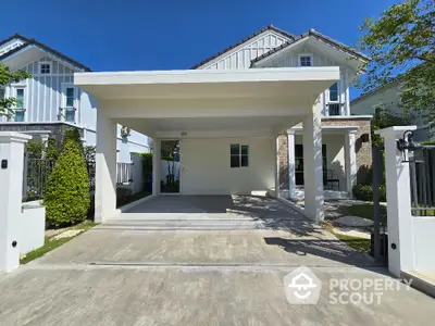 Modern two-story house with spacious driveway and lush greenery in a serene neighborhood.