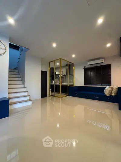Spacious modern living room with sleek staircase and stylish glass partition, perfect for contemporary living.
