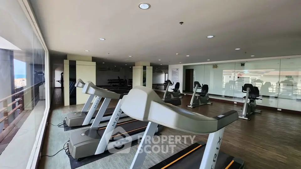 Spacious gym with modern treadmills and large windows offering a scenic view, perfect for fitness enthusiasts.