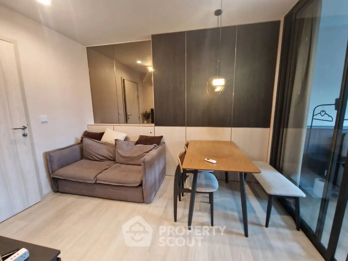 Modern living room with cozy sofa and dining area, featuring elegant lighting and stylish decor.