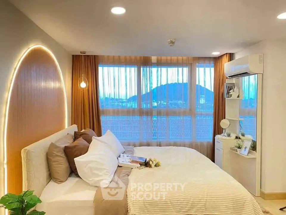 Cozy bedroom with modern decor and large window offering scenic view.