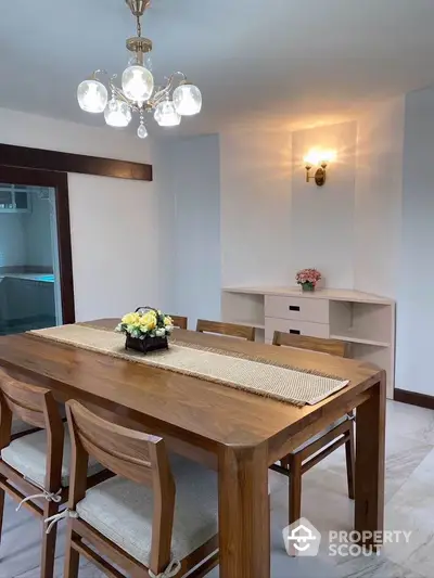 Elegant dining room with wooden table and chairs, featuring a stylish chandelier and wall sconce lighting.