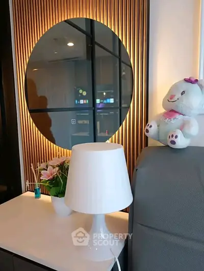 Modern interior with stylish lamp, decorative mirror, and plush toy in cozy living space.