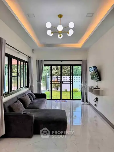 Modern living room with large windows and stylish lighting, featuring a cozy sectional sofa and garden view.