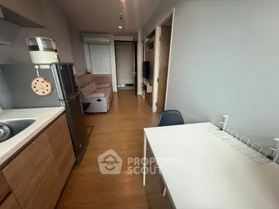 Modern apartment interior with open layout kitchen and cozy living area, featuring sleek wooden flooring.