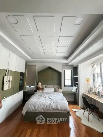 Modern bedroom with stylish ceiling design, cozy bed, and functional workspace, perfect for urban living.