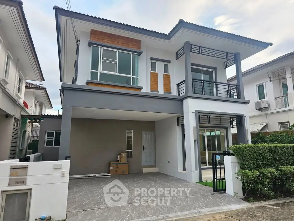 Modern two-story house with balcony and garage in a suburban neighborhood.