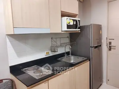 Modern kitchen with sleek cabinets, electric stove, and stainless steel fridge.