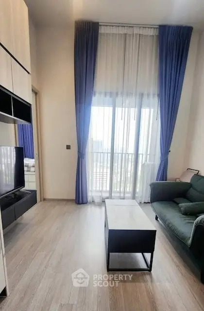 Modern living room with high ceilings, large windows, and elegant blue curtains.