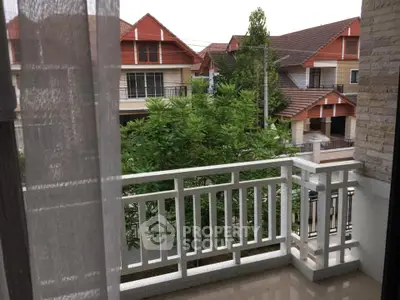 Charming balcony view with lush greenery and neighboring houses.