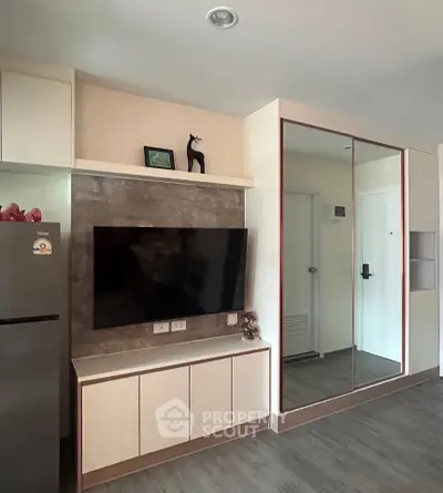 Modern living room with sleek TV setup and mirrored wardrobe in stylish apartment.