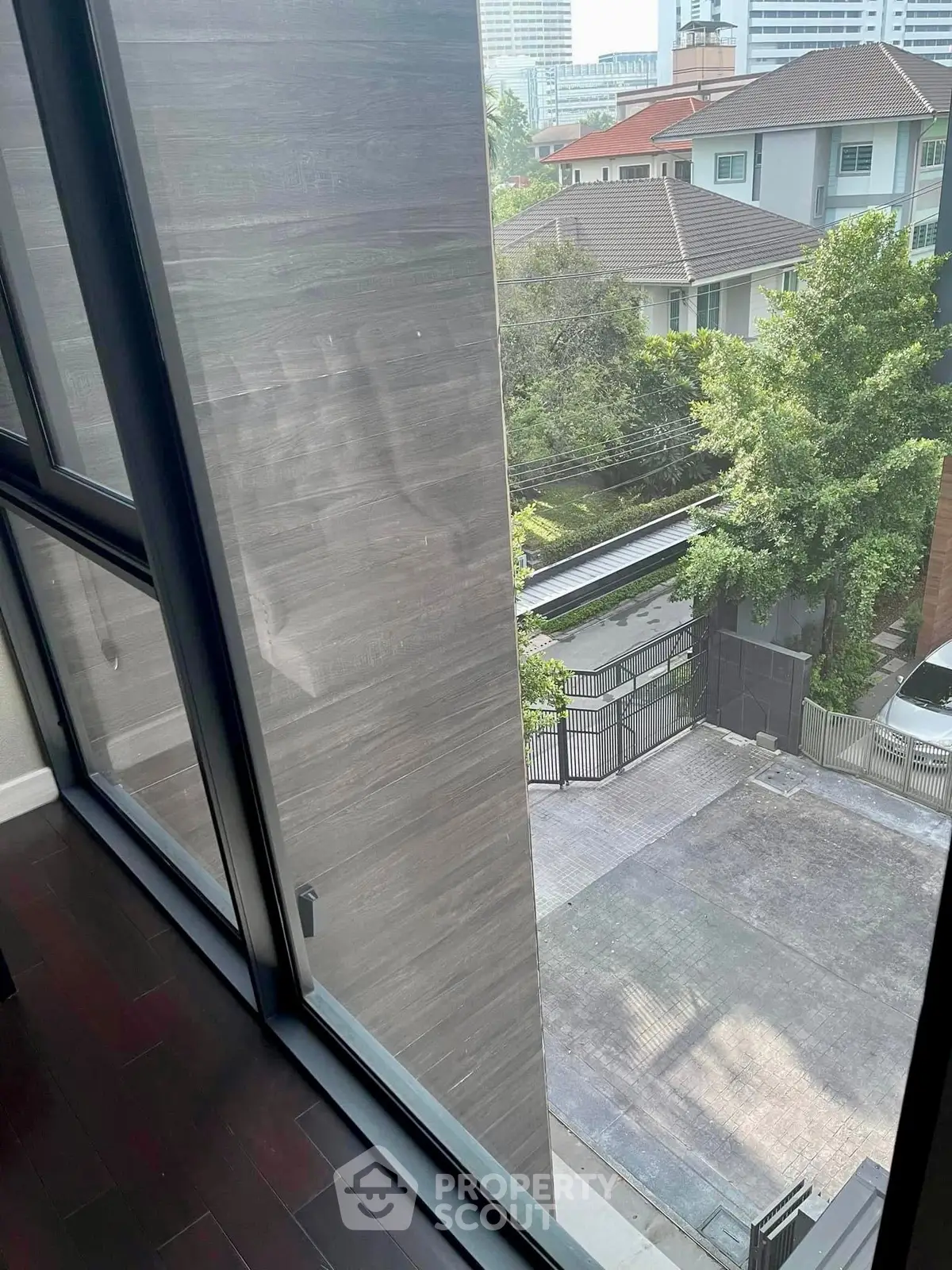 Modern apartment view with large windows overlooking urban neighborhood and greenery.
