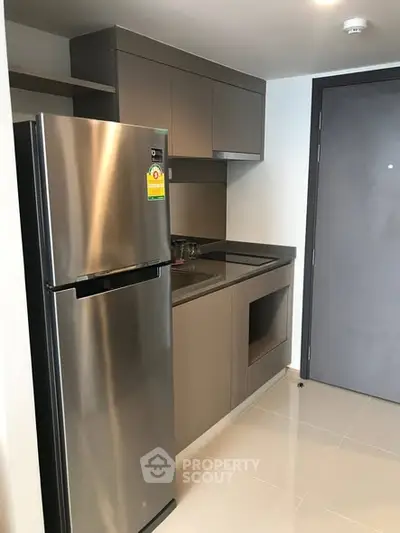 Modern kitchen with sleek cabinetry and stainless steel fridge in compact layout.