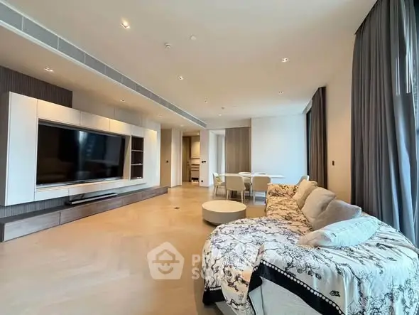 Spacious modern living room with elegant decor and large TV, perfect for relaxation and entertainment.