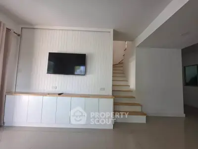 Modern living room with wall-mounted TV and stylish staircase