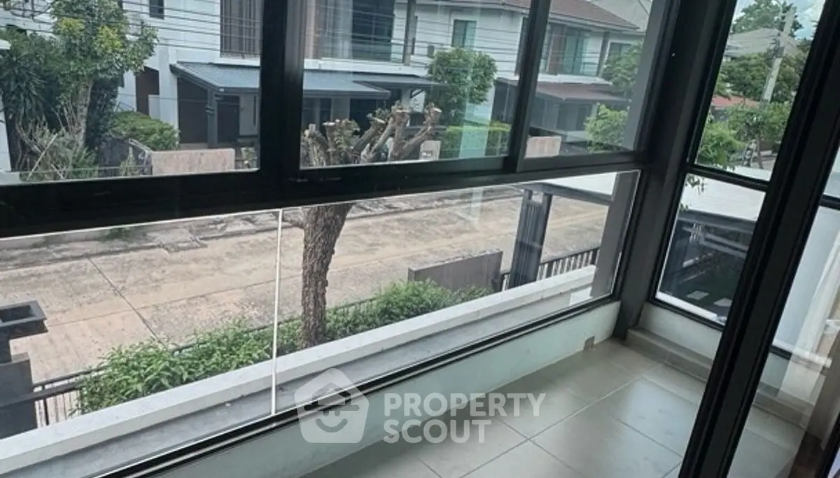 Spacious balcony with large windows overlooking a quiet residential street.