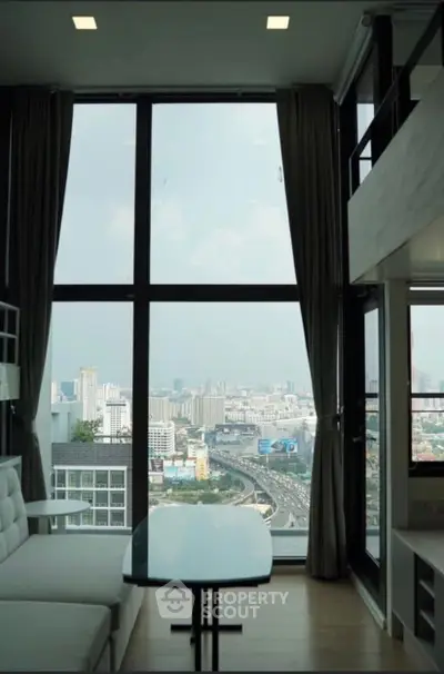 Stunning high-rise living room with floor-to-ceiling windows offering panoramic city views.