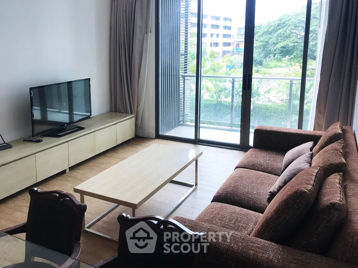 Spacious living room with modern furniture and large windows opening to a balcony with a view.