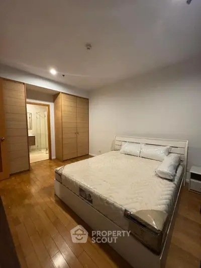 Spacious bedroom with wooden flooring and ensuite bathroom in modern apartment