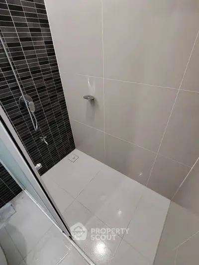 Modern bathroom shower area with sleek black and white tiles.