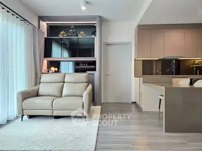 Modern living room with sleek design and open kitchen layout, featuring neutral tones and stylish furniture.
