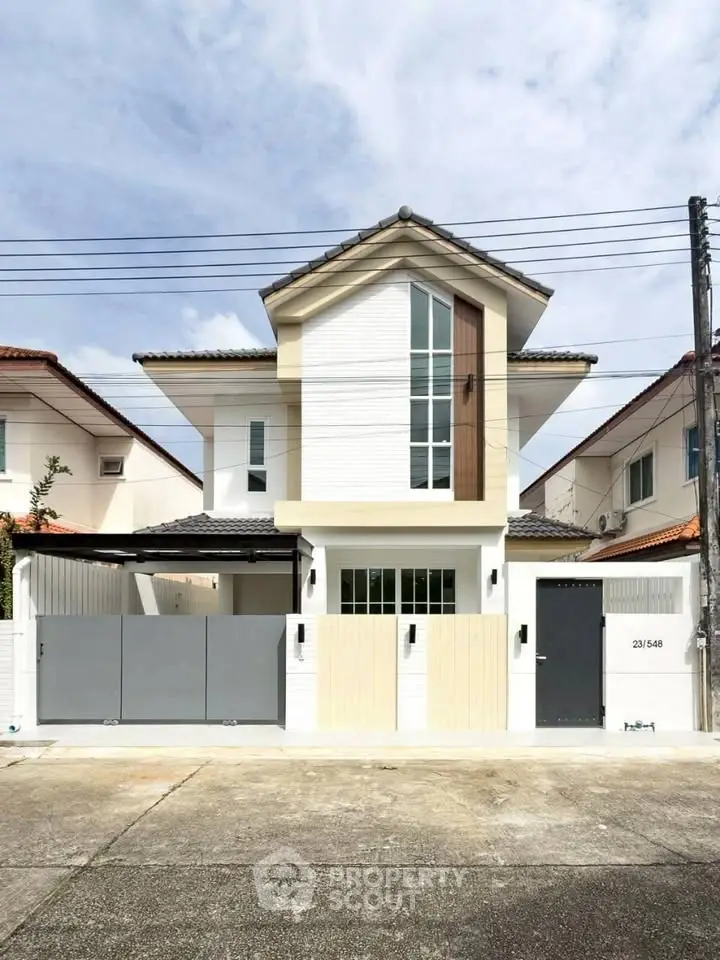 Modern two-story house with sleek design and gated entrance in a suburban neighborhood.