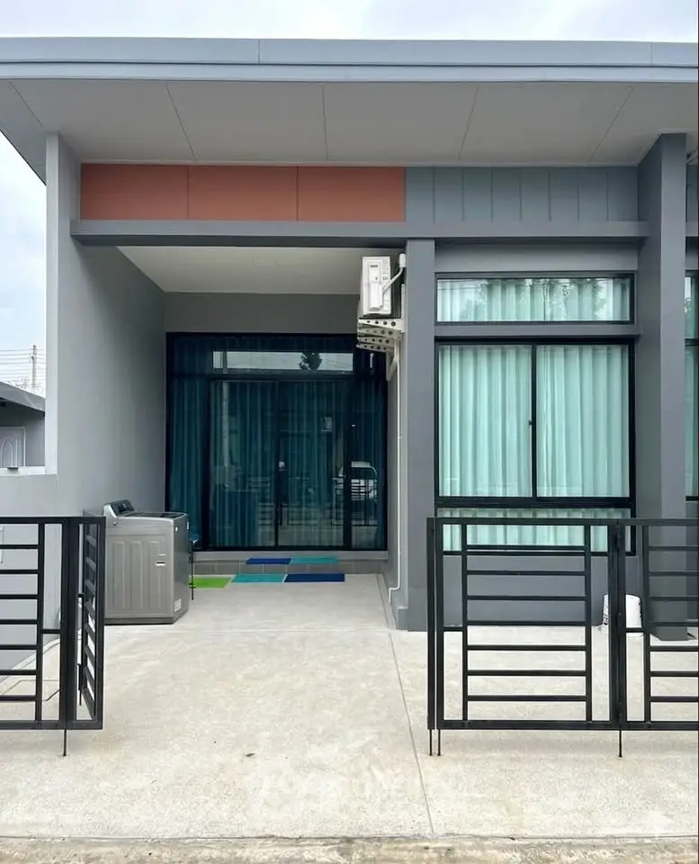 Modern single-story house with sleek design and large windows, featuring a gated entrance and minimalist exterior.