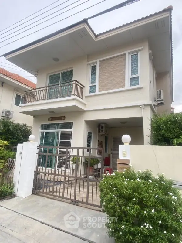 Charming two-story house with balcony and gated entrance in a suburban neighborhood.