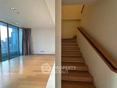 Spacious modern living room with wooden flooring and city view balcony access.