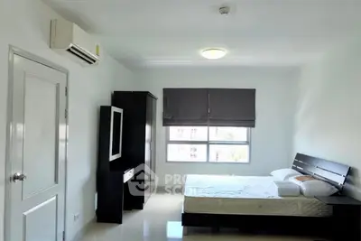 Spacious bedroom with modern furniture and large window for natural light.