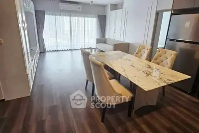 Modern open-plan living and dining area with elegant marble table and plush seating.