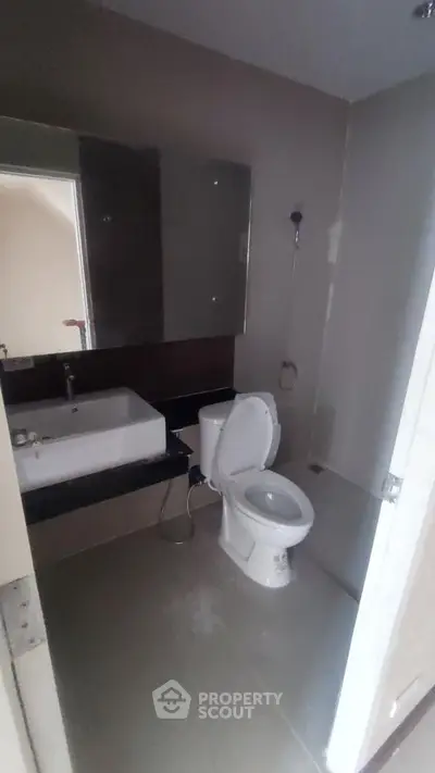 Modern bathroom with sleek fixtures and neutral tones, featuring a large mirror and spacious shower area.