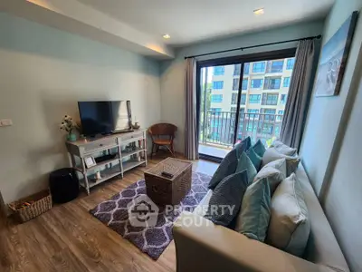 Charming living room with cozy decor and balcony view in modern apartment.
