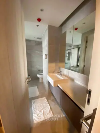Modern bathroom with sleek fixtures and large mirror in a contemporary apartment.