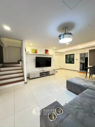 Spacious modern living room with sleek design and elegant lighting, featuring a cozy sectional sofa and entertainment center.