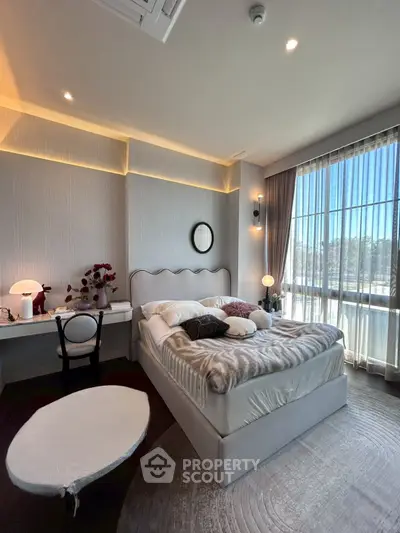 Luxurious bedroom with elegant decor and large windows offering natural light and scenic views.