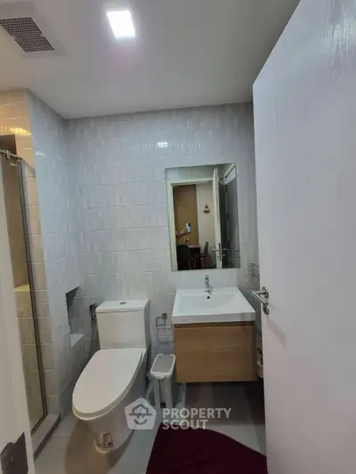 Modern bathroom with sleek fixtures and large mirror in contemporary apartment.