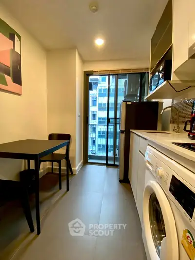 Modern kitchen with washing machine and dining area in a high-rise apartment.