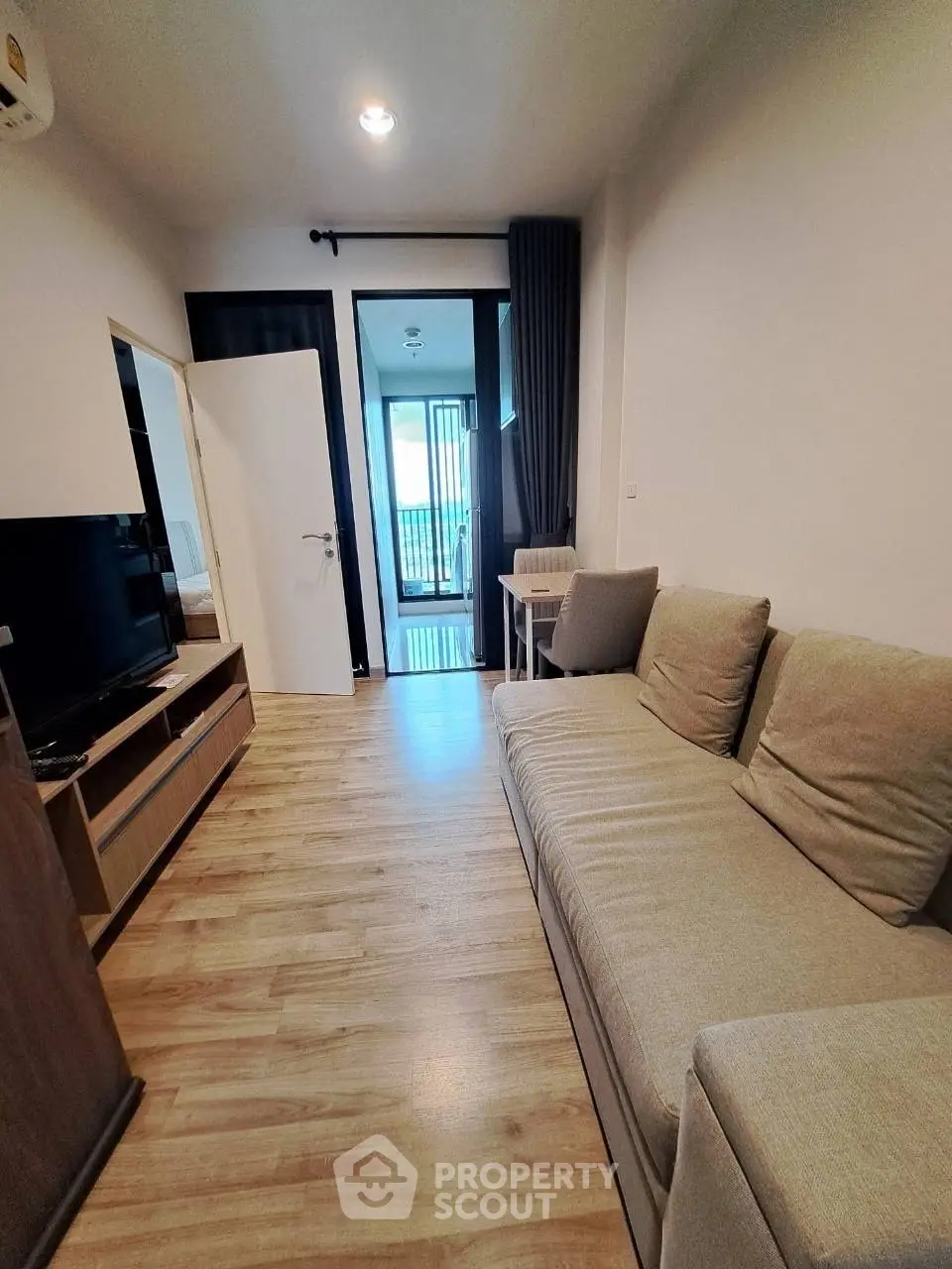 Modern living room with cozy sofa and wooden flooring leading to a balcony.