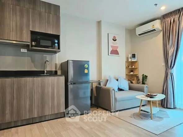 Modern living room with compact kitchen, featuring sleek cabinetry and cozy seating area.